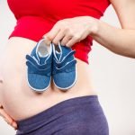 Pregnant woman with baby shoes, expecting for baby